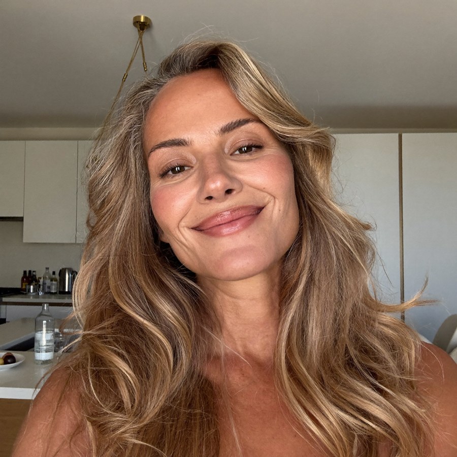 Selfie d'Isabelle, début de la cinquantaine, peau rayonnante et rebondie, cheveux volumineux, souriant dans sa cuisine
